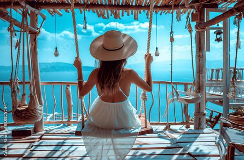 ravel summer vacation or holiday concept. Happy traveler young and beautiful woman with hat and dress relax on swing in beachside hotel or beach cafe photo