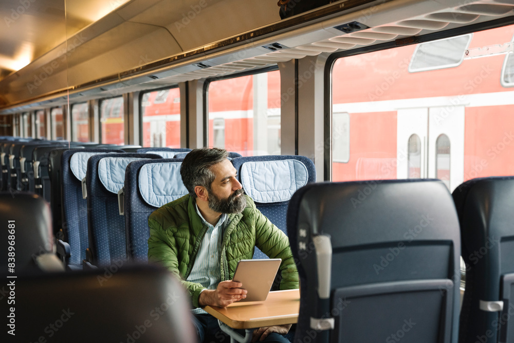 Man sitting in train holding tablet