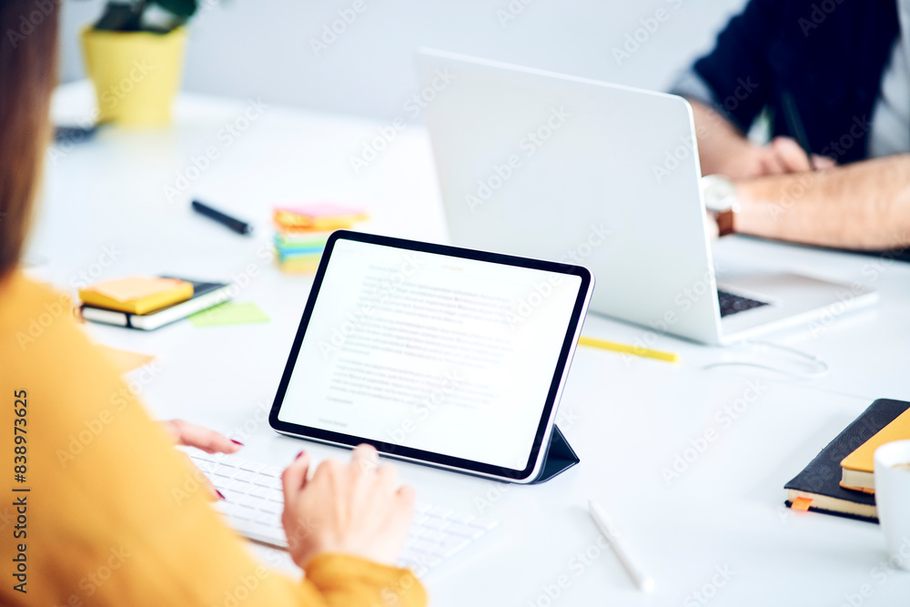 Close-up of businesswoman using tablet at desk in office Close-up of businesswoman using tablet at desk in office