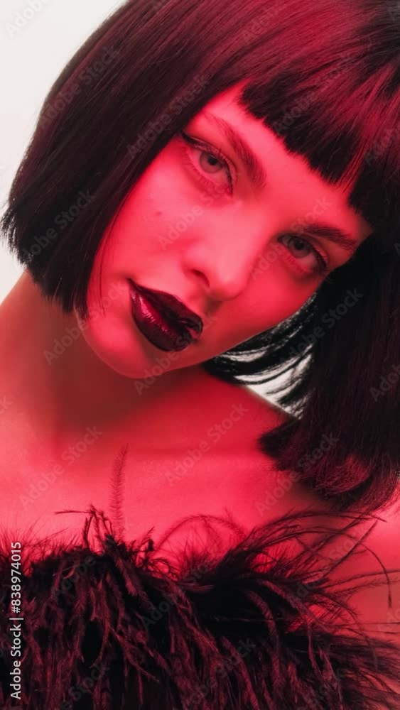 Portrait of a girl in red light with black lips and a wig on a white background in the studio. Woman in neon creative light. Portrait of a girl in red light with black lips and a wig on a white background in the studio. Woman in neon creative light.