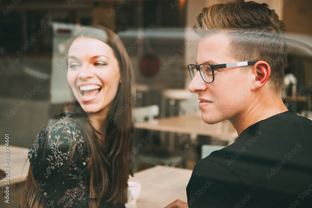 Couple sitting in a coffee shop looking through window Couple sitting in a coffee shop looking through window