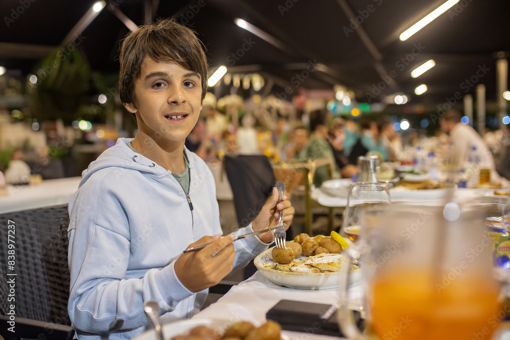 Cute child, boy, eating fish for dinner in a restaurant in Portugal