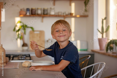 Cute blond child, boy, eating soup at home for dinner, summertime