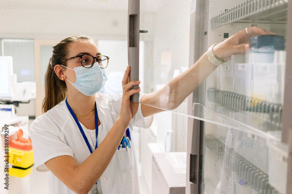 Female doctor taking medicines from cabinet in pharmacy at hospital