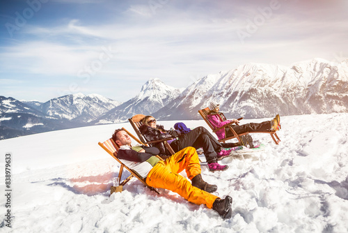 Obraz na płótnie Friends sunbathing in deck chairs in mountainscape in winter, Achenkirch, Austria w salonie