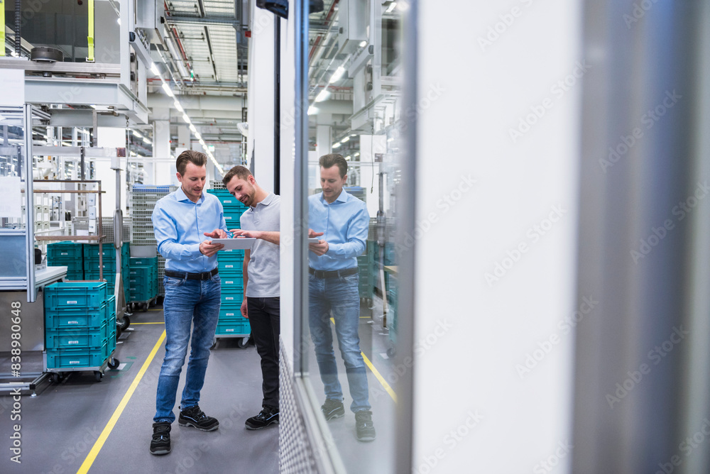 Two men with tablet talking in factory shop floor Two men with tablet talking in factory shop floor