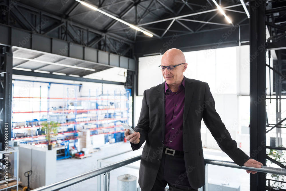 Businessman with cell phone on factory shop floor Businessman with cell phone on factory shop floor