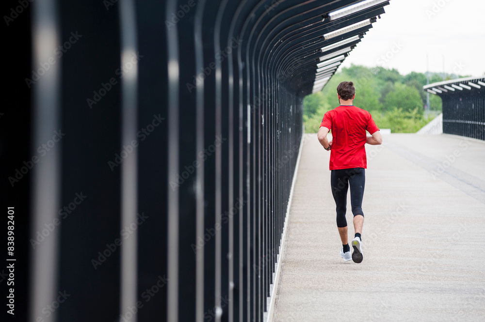 Rear view of man running on a bridge Rear view of man running on a bridge