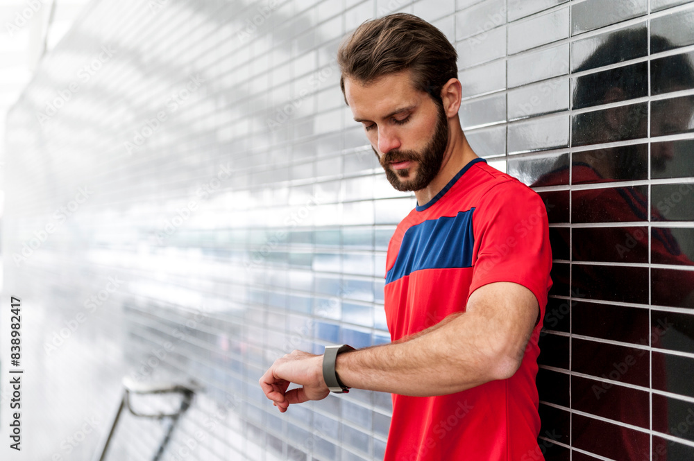 Man having a break from running checking the time on a smartwatch