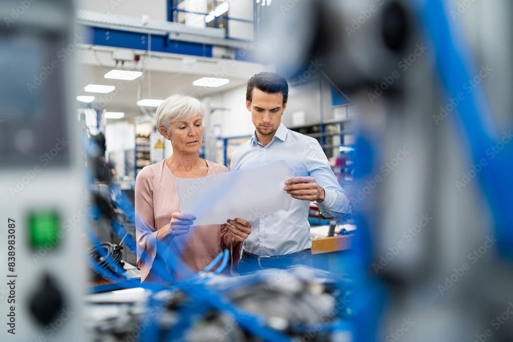 Businessman and senior woman looking at plan in a factory