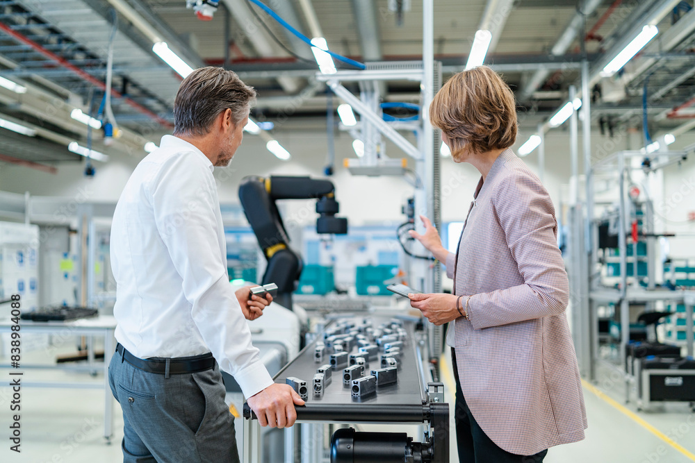 Businessman and businesswoman talking in a modern factory hall