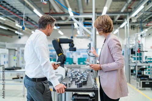 Obraz na płótnie Businessman and businesswoman talking in a modern factory hall w salonie