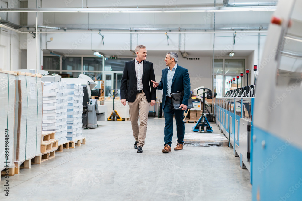 Two businessmen walking and talking in a factory