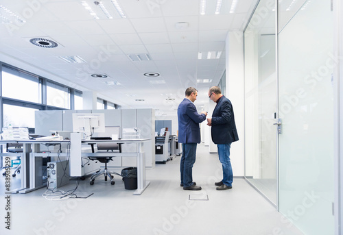 Two businessmen standing in office looking at smartphone © tunedin