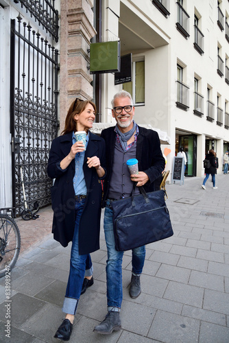 Smiling mature couple with reusable bamboo cups walking in the city photo