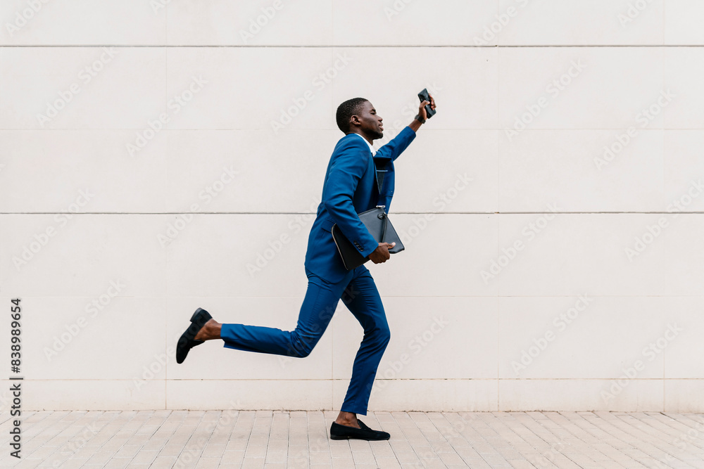 Young male professional running on sidewalk by wall in city Young male professional running on sidewalk by wall in city