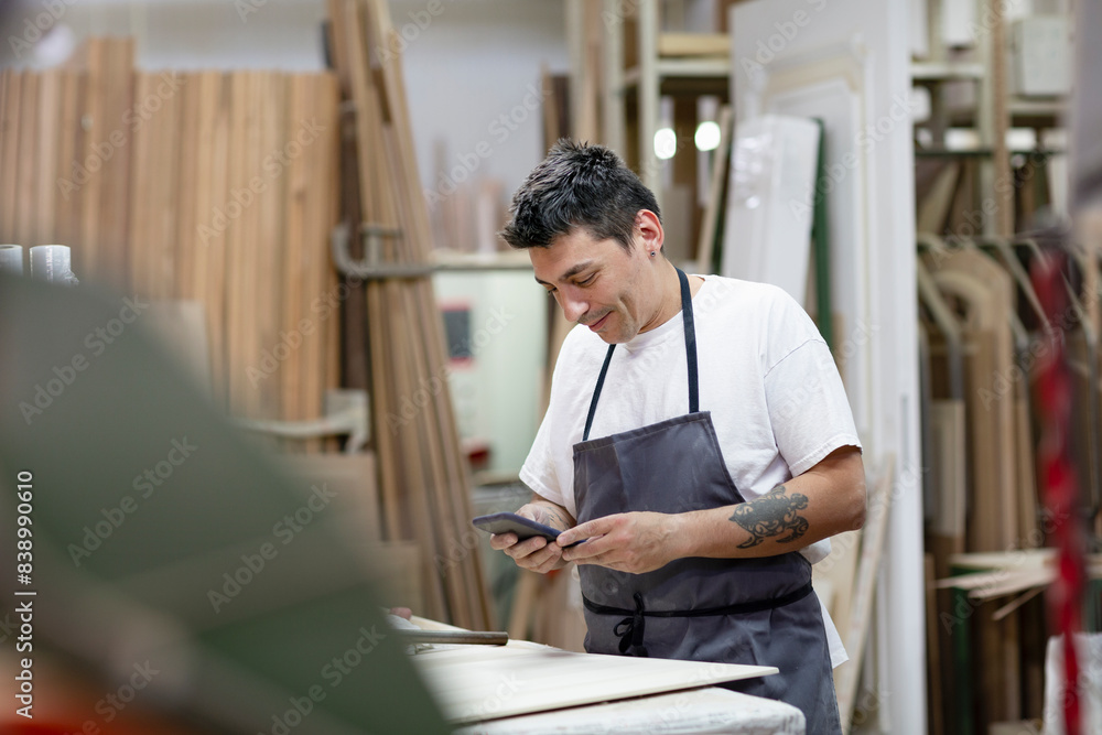 Male artist using mobile phone while standing at workshop Male artist using mobile phone while standing at workshop