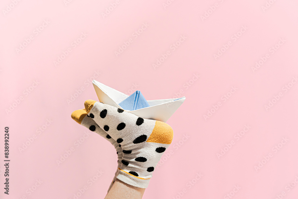 Paper boat on the feet of a girl wearing dotted socks