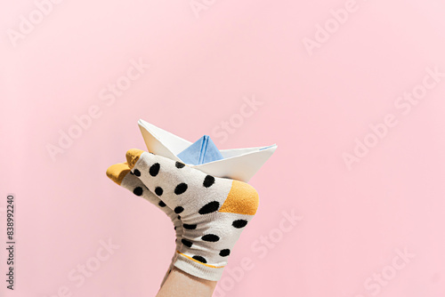 Obraz na płótnie Paper boat on the feet of a girl wearing dotted socks w salonie