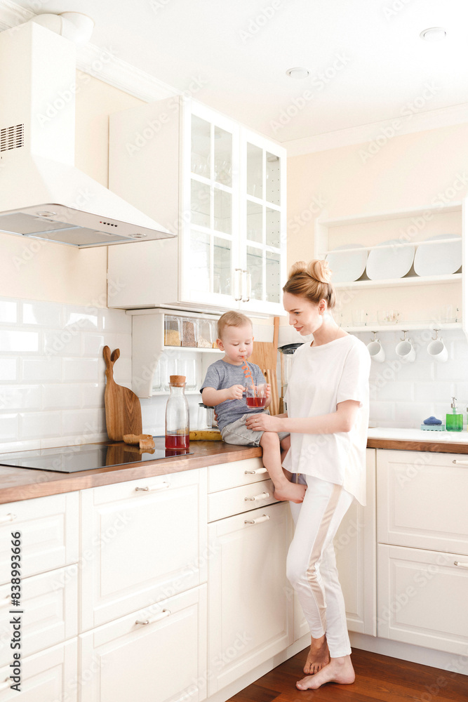 Mother with her little boy drinking a juice in the kitchen Mother with her little boy drinking a juice in the kitchen
