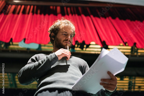 Obraz na płótnie Portrait of pensive man standing on stage of theatre looking at script w salonie