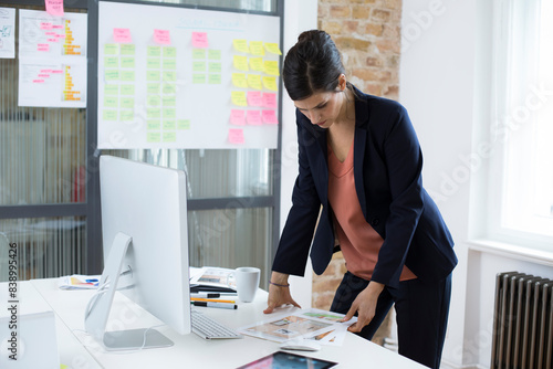 Businesswoman at desk in office looking at printouts
