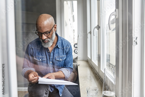 Mature man plying with paper plane photo