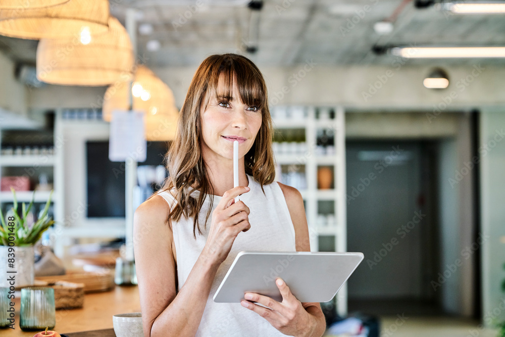 Thoughtful woman holding digitized pen and digital tablet while standing art home