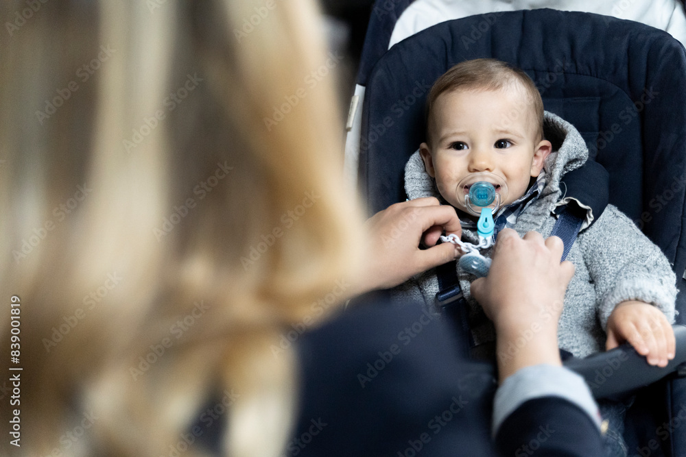 Portrait of baby boy with pacifier in strollerwatching his mother Portrait of baby boy with pacifier in strollerwatching his mother