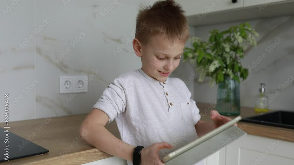 Young Boy Enjoys Playing on Tablet in Modern Kitchen During Afternoon Young Boy Enjoys Playing on Tablet in Modern Kitchen During Afternoon