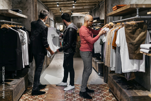 Three men in modern menswear shop with new collection