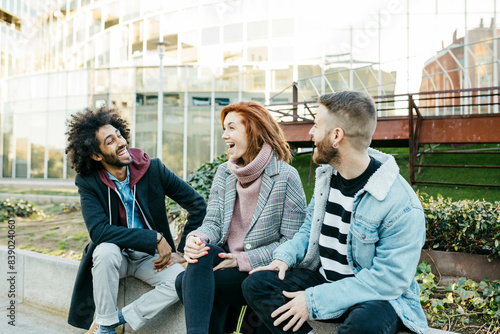 Three happy friends sitting in the city talking photo