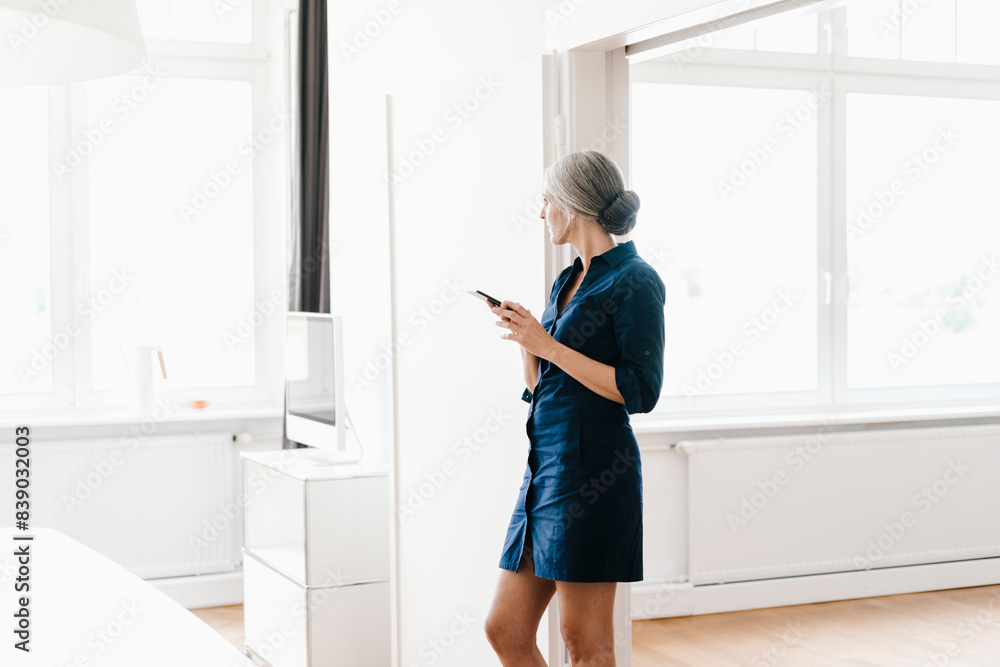 Businesswoman in office looking out of window Businesswoman in office looking out of window