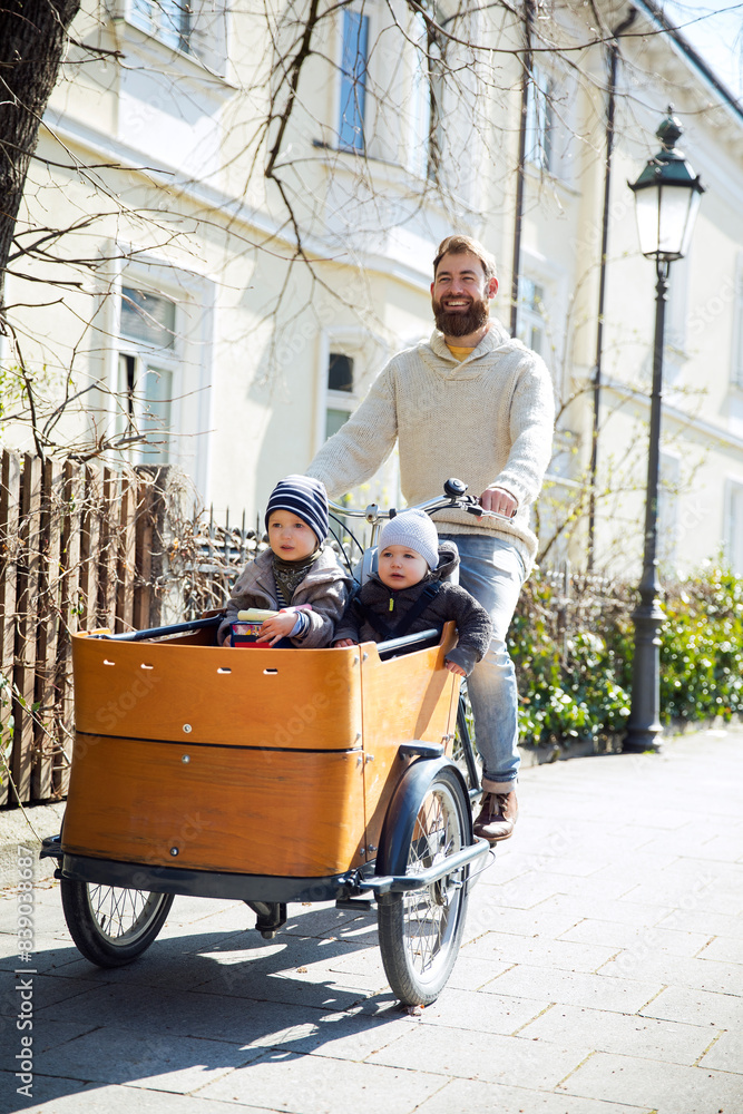 Happy father with two children riding cargo bike in the city