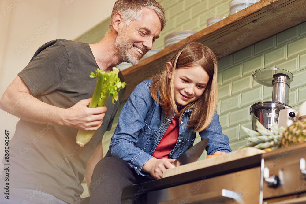 Fototapeta premium Happy father and daughter in kitchen preparing vegetables