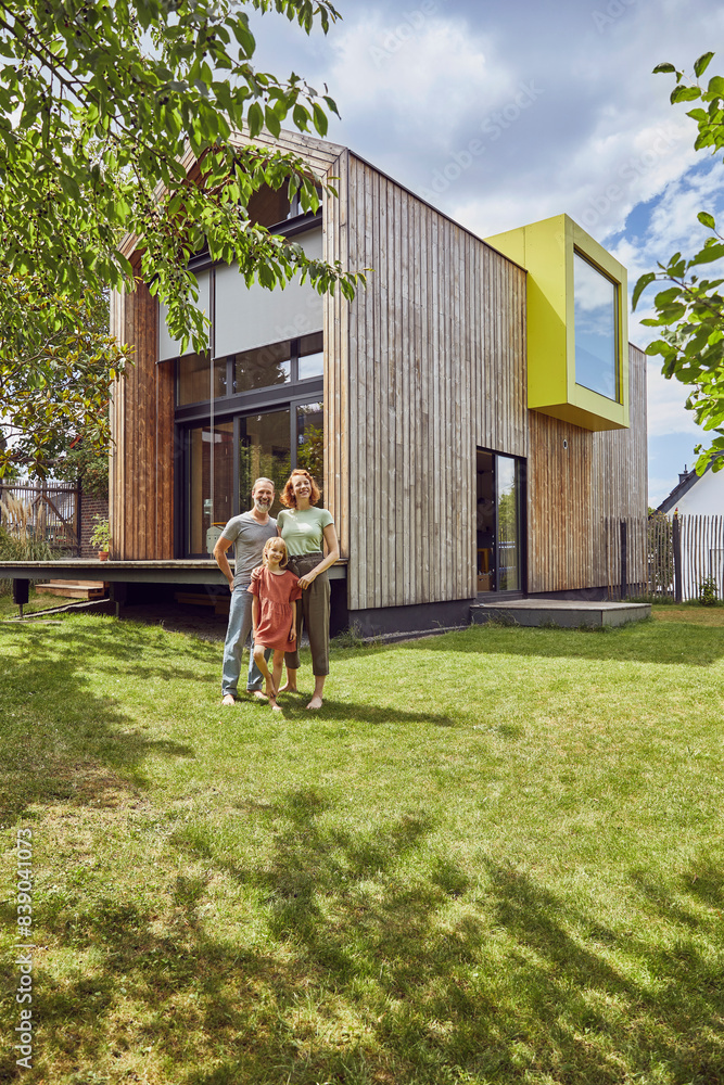 Family standing on grassy land in front of tiny house