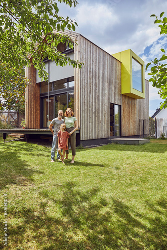 Obraz na płótnie Family standing on grassy land in front of tiny house w salonie