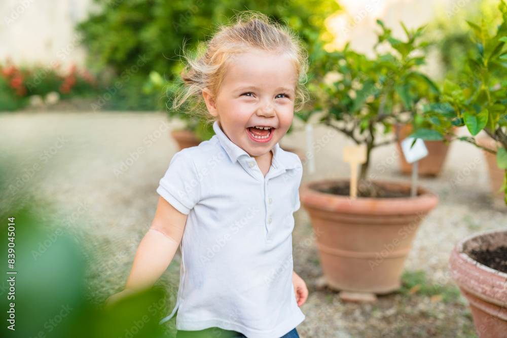Happy little girl running along flower pots Happy little girl running along flower pots