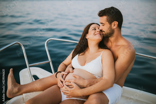 Romantic couple with pregnat woman sitting on boat photo