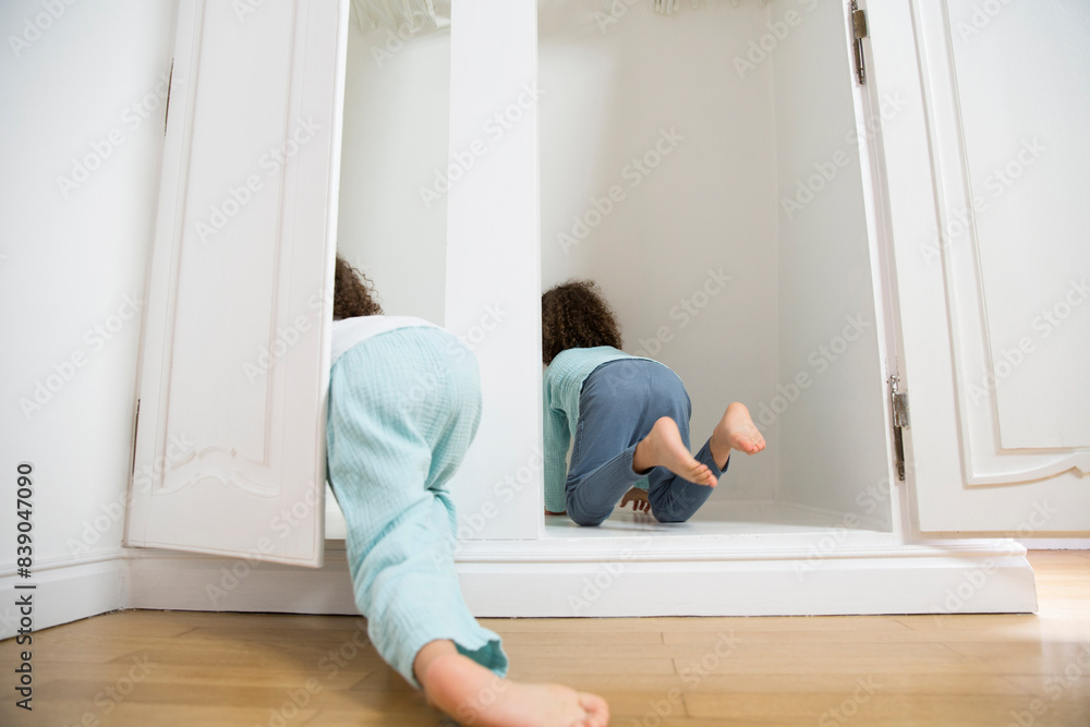 Two twin brothers crawling into wardrobe at home Two twin brothers crawling into wardrobe at home