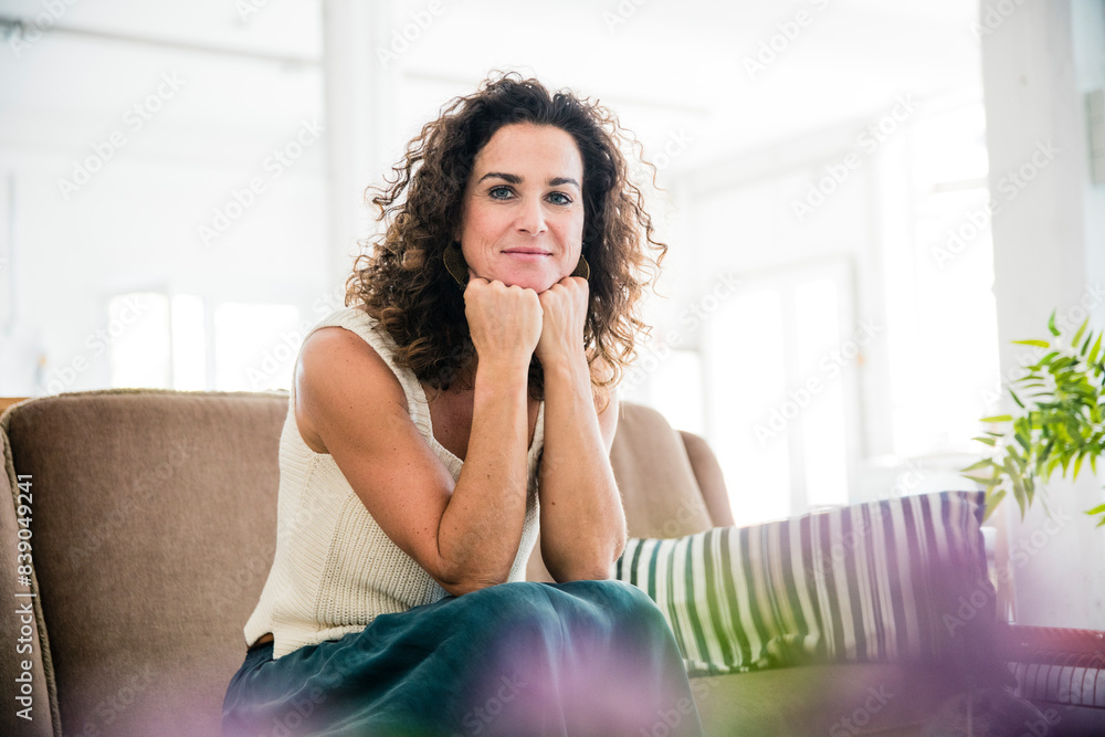 Confident woman sitting on her couch, smiling Confident woman sitting on her couch, smiling