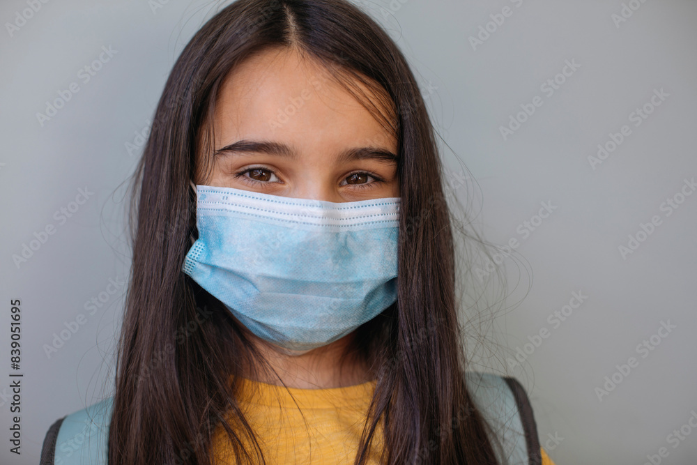 Girl with protective face mask standing against gray wall Girl with protective face mask standing against gray wall