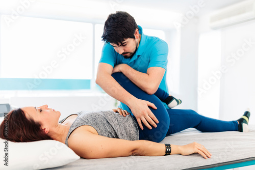 Male visually impaired physical therapist treating woman's leg in clinic