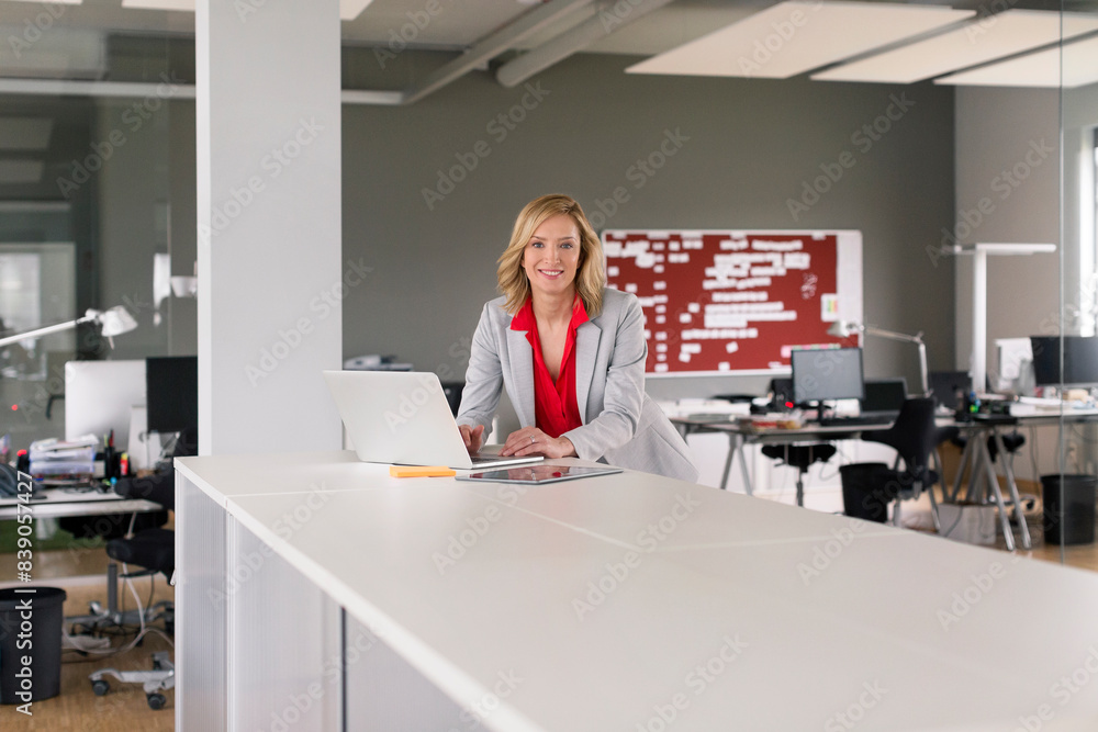 Portrait of smiling businesswoman using laptop in office Portrait of smiling businesswoman using laptop in office