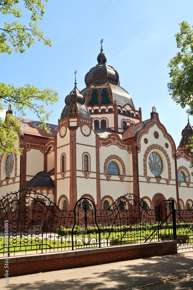 Obraz premium The Synagogue of Subotica behind a black metal fence with elaborate details on a sunny day, Subotica, Serbia