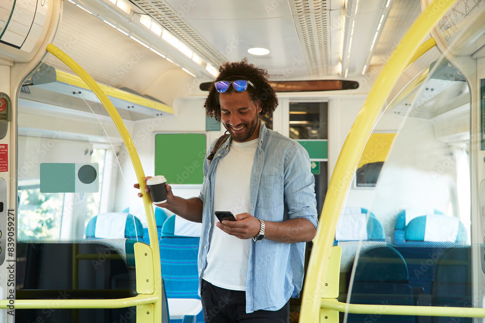 Young trendy man smiling while using smart phone in train Young trendy man smiling while using smart phone in train
