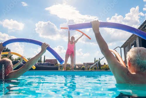 Group of seniors with trainer doing water gymnastics in pool photo