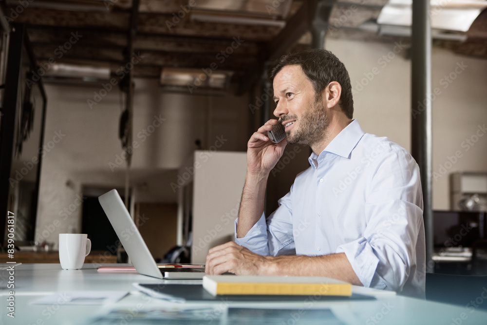 Businessman at desk with laptop and phone