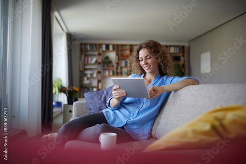 Woman using digital tablet while sitting on sofa at home © tunedin