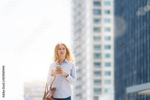 Blond woman with handbag and cell phone walking through the city